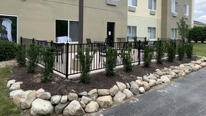 Un edificio residencial de varios pisos con balcón, zona de estar al aire libre y jardín de rocas.