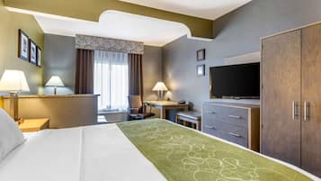 Een hotelkamer met een bed, twee bedlampen, een bureau met stoel, een televisie en een kledingkast.