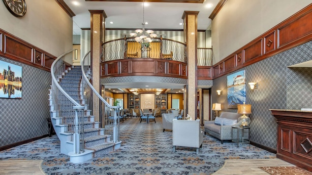 A spacious lobby with a grand staircase, a second-floor balcony, and a reception area.