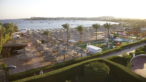 A coastal resort with beach umbrellas, lounge chairs, and a marina. - Gafy Resort Aqua Park (Sharm El Sheikh)