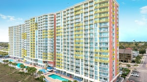 A multi-story hotel with balconies, a swimming pool, and a parking area.