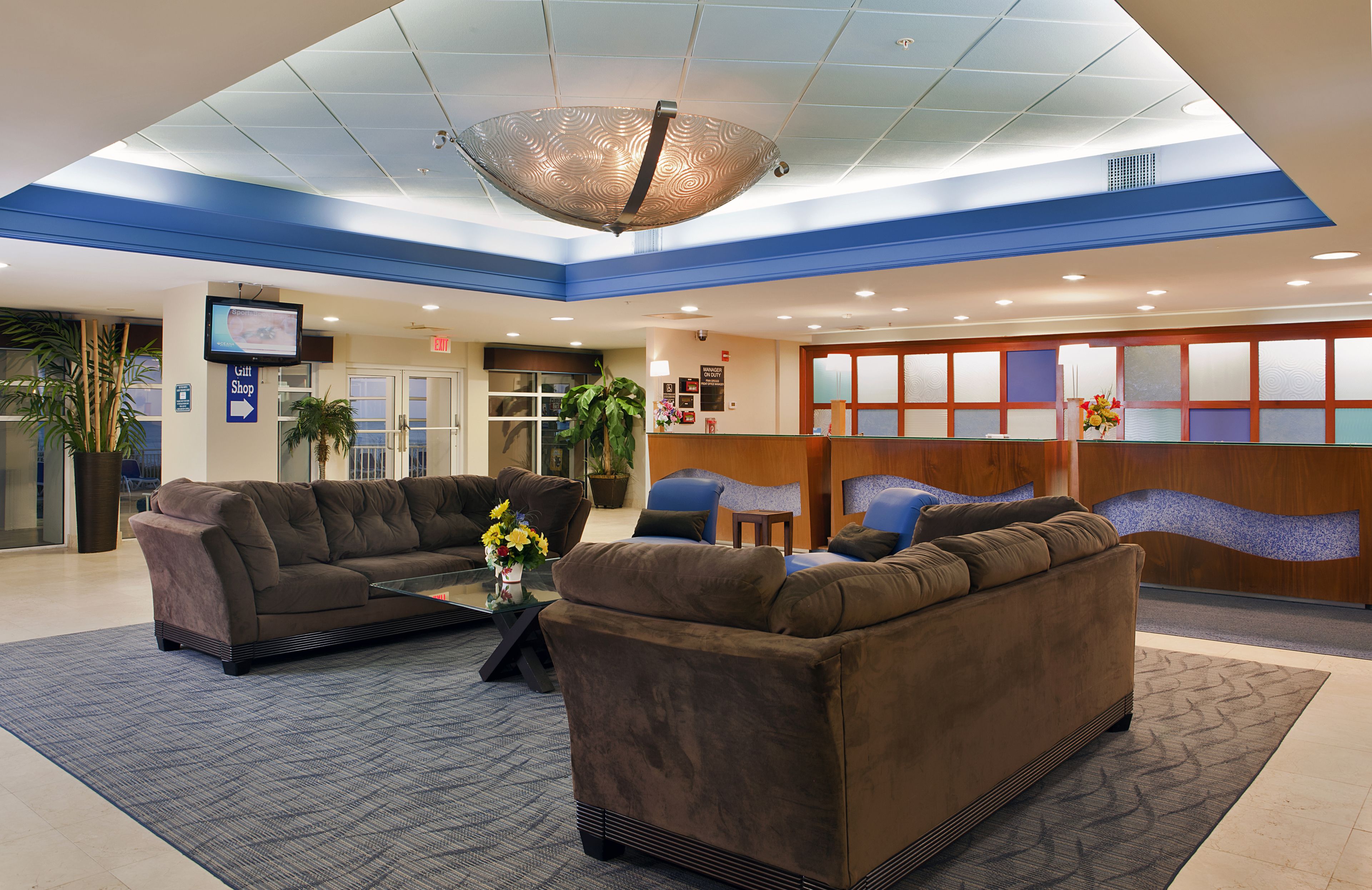 A lobby with a reception desk, two sofas, a coffee table, and a large ceiling light fixture.