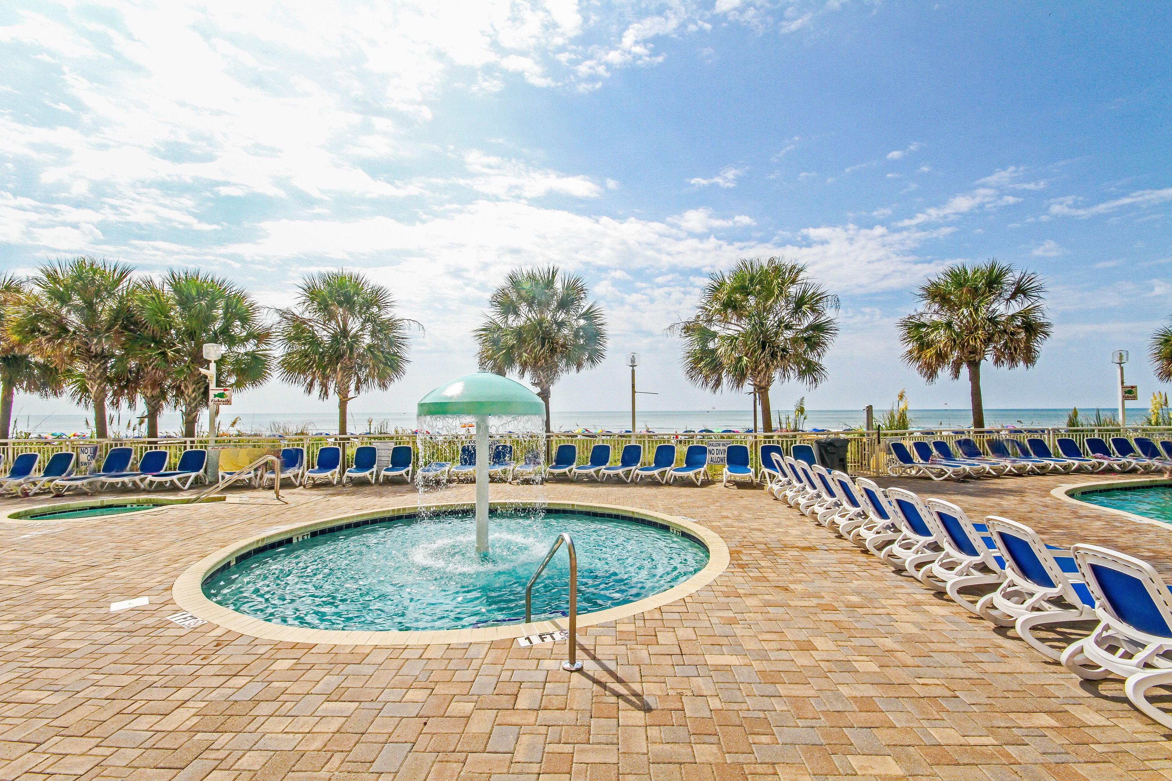 A pool area with lounge chairs and palm trees.