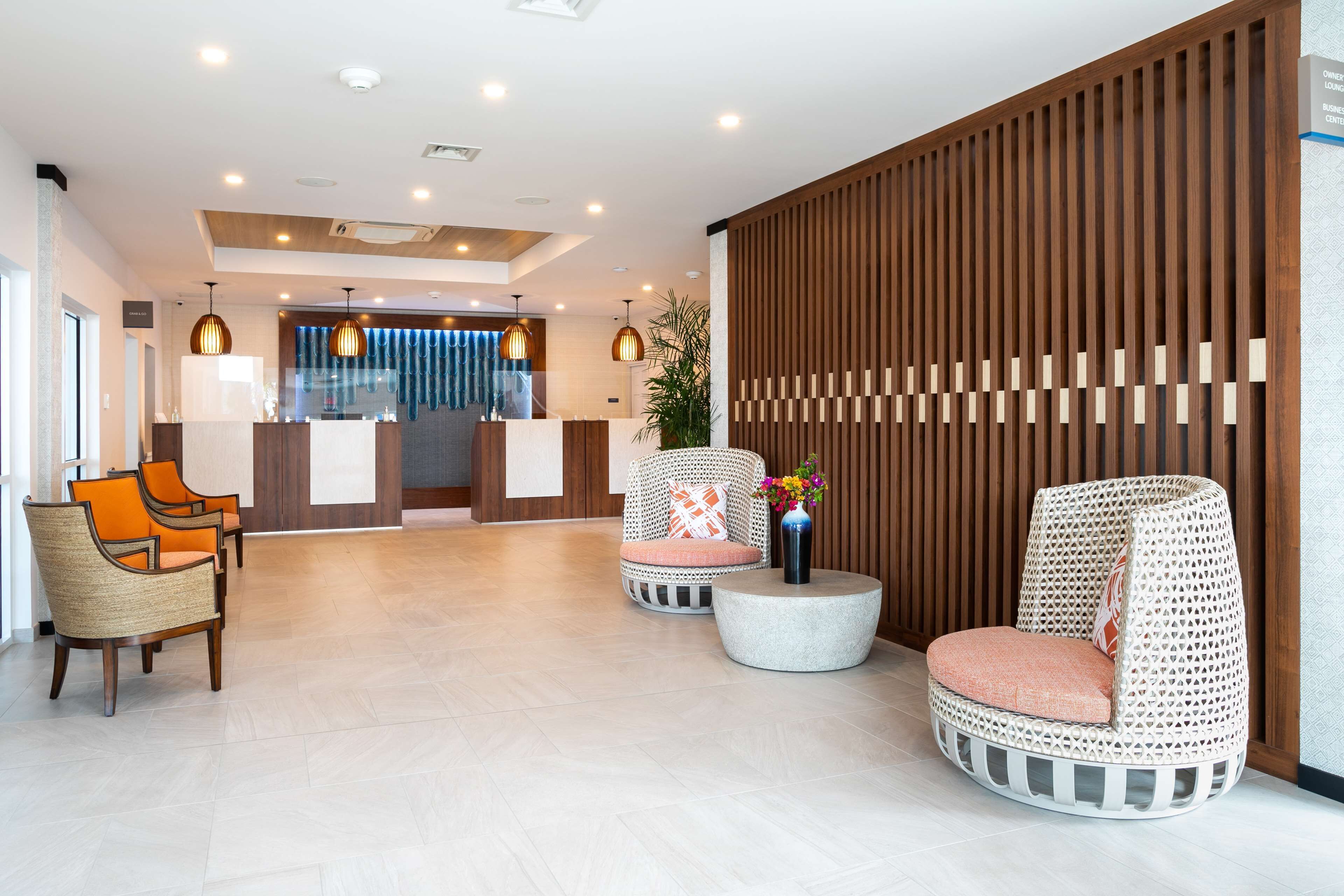 Eine moderne Lobby mit Rattanmöbeln, einem Empfangstresen und einer Holztrennwand.