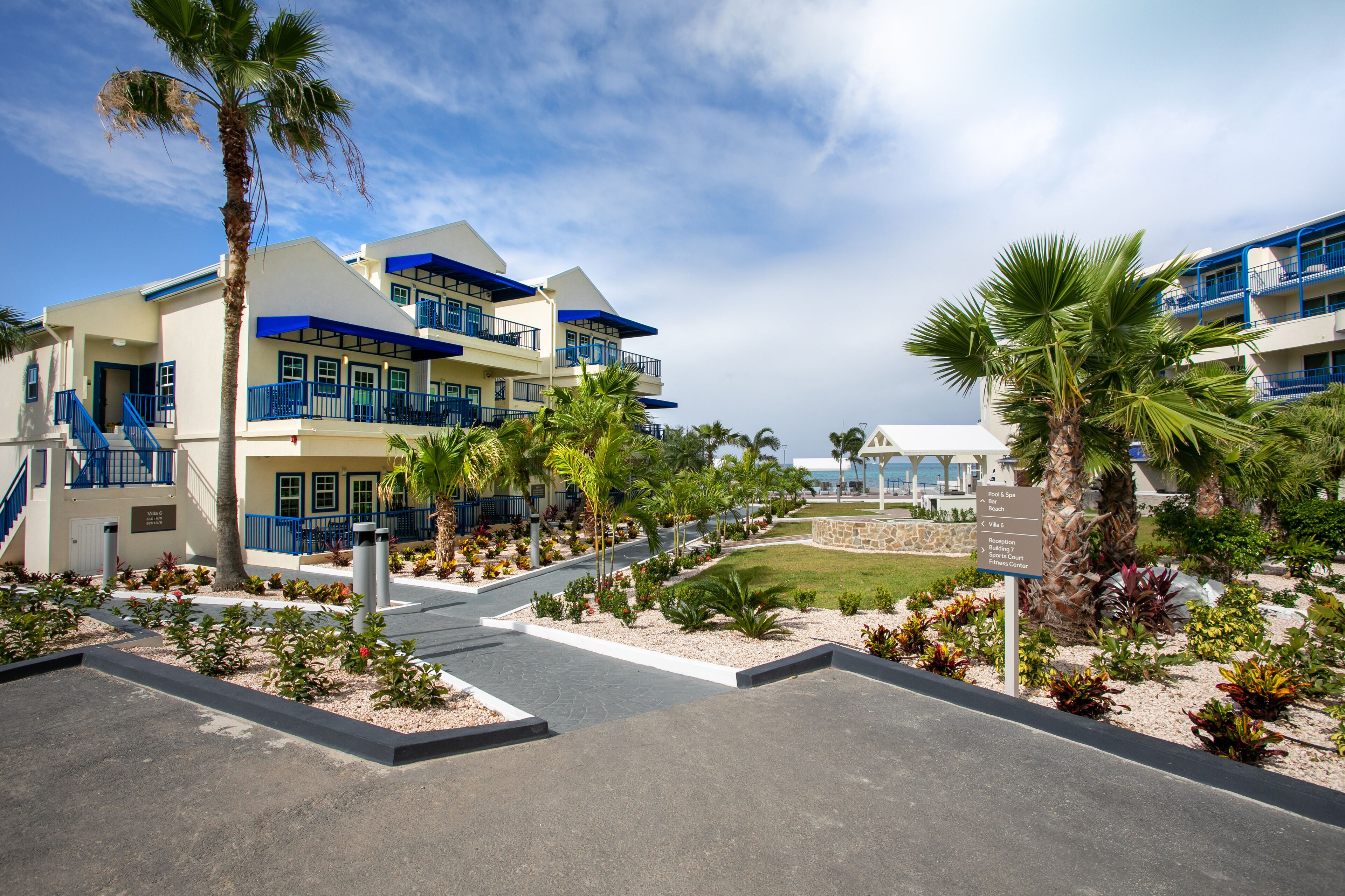 A resort with multiple-story buildings, palm trees, and a well-maintained garden area.