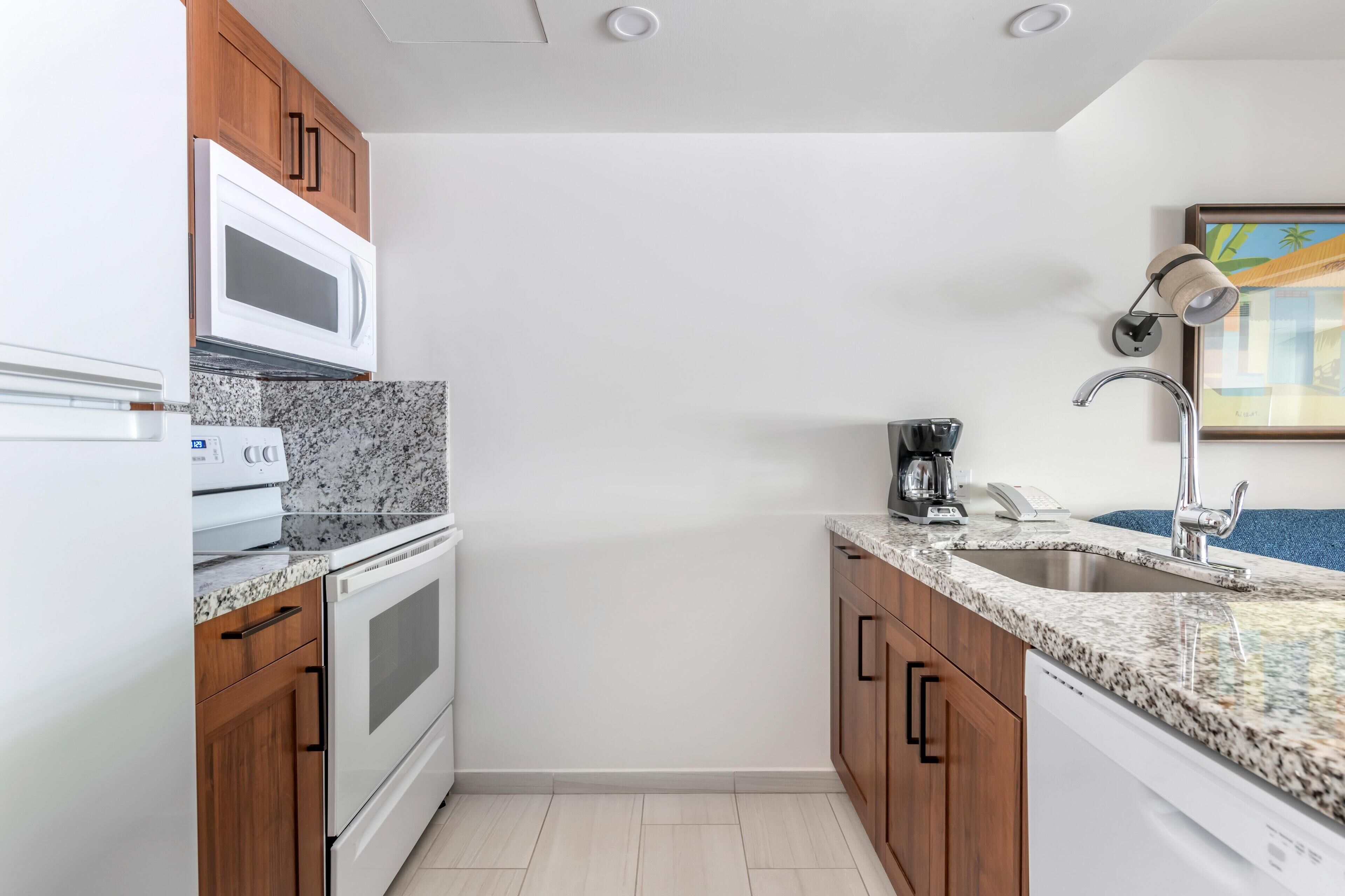 A compact kitchen with a microwave, stove, and sink.