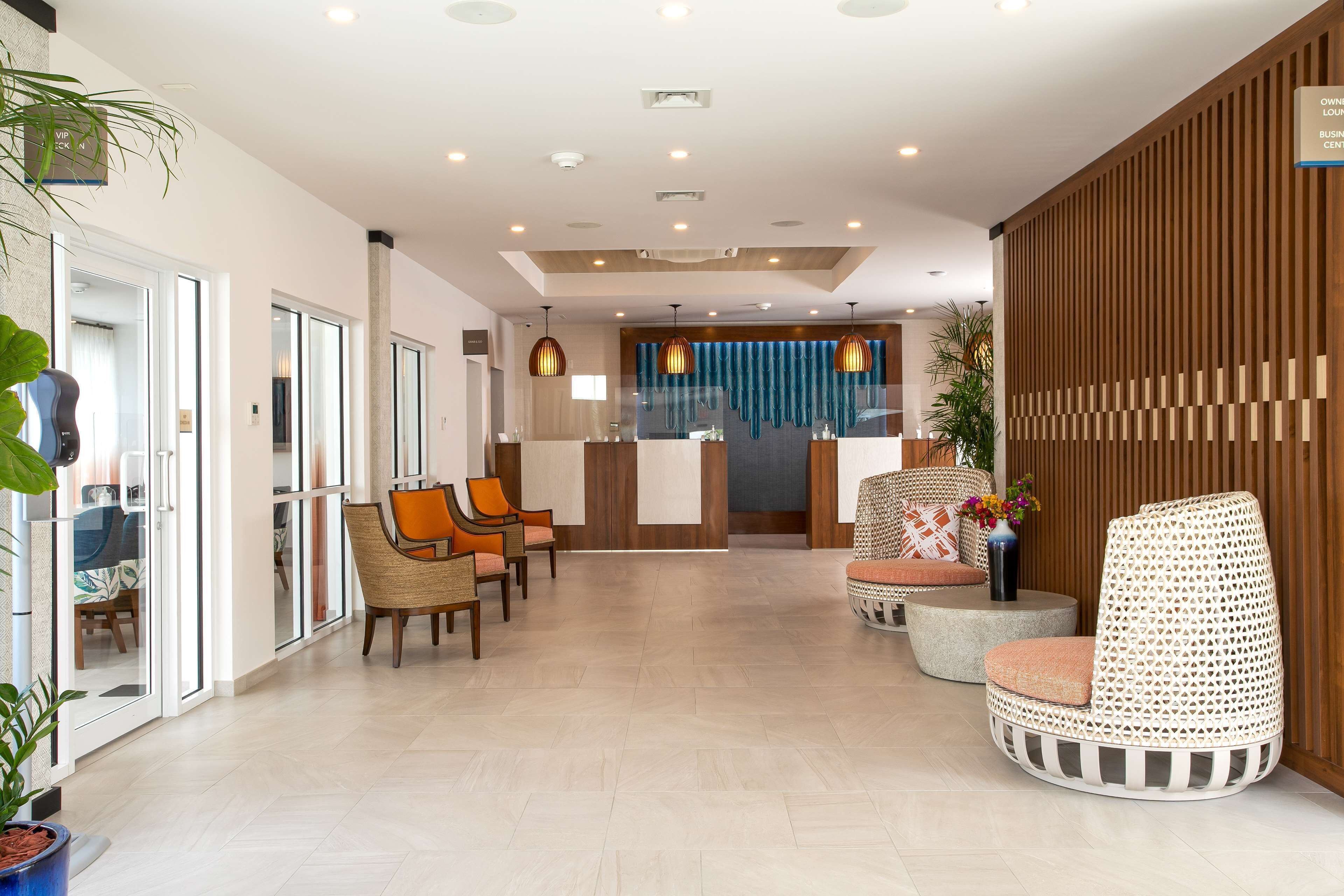 A modern lobby with a reception desk, seating area, and a wooden partition.
