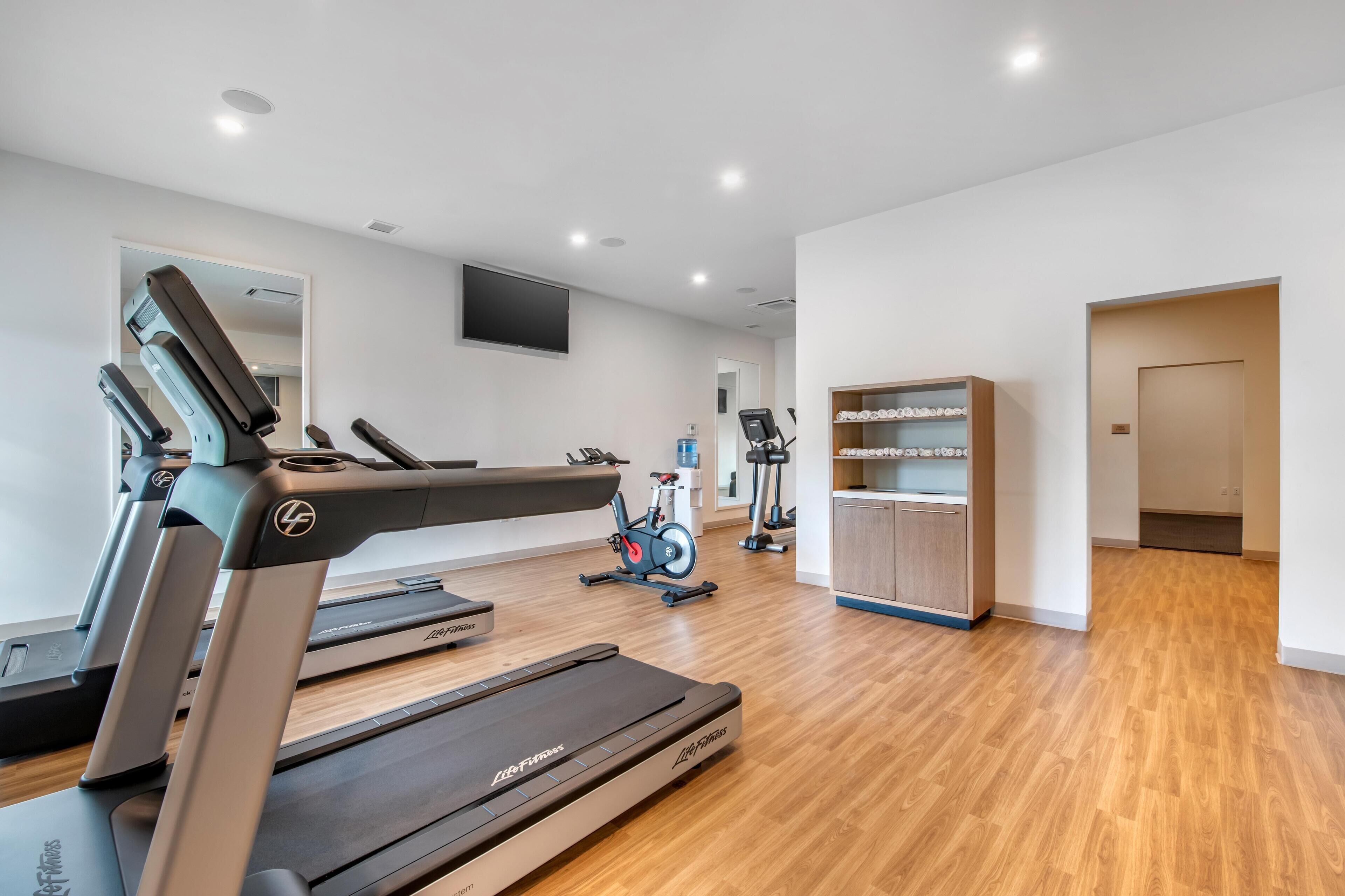 A modern gym with treadmills, an exercise bike, and a water dispenser.
