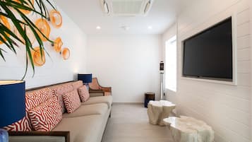 A modern living room with a sofa, a television, and decorative elements like a plant and wall art.