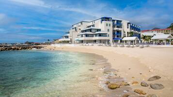 Un hotel sulla spiaggia con numerosi balconi, lettini prendisole e vista libera sull'oceano.