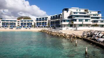 Um hotel à beira-mar com várias varandas, águas azul-claras e um litoral rochoso.