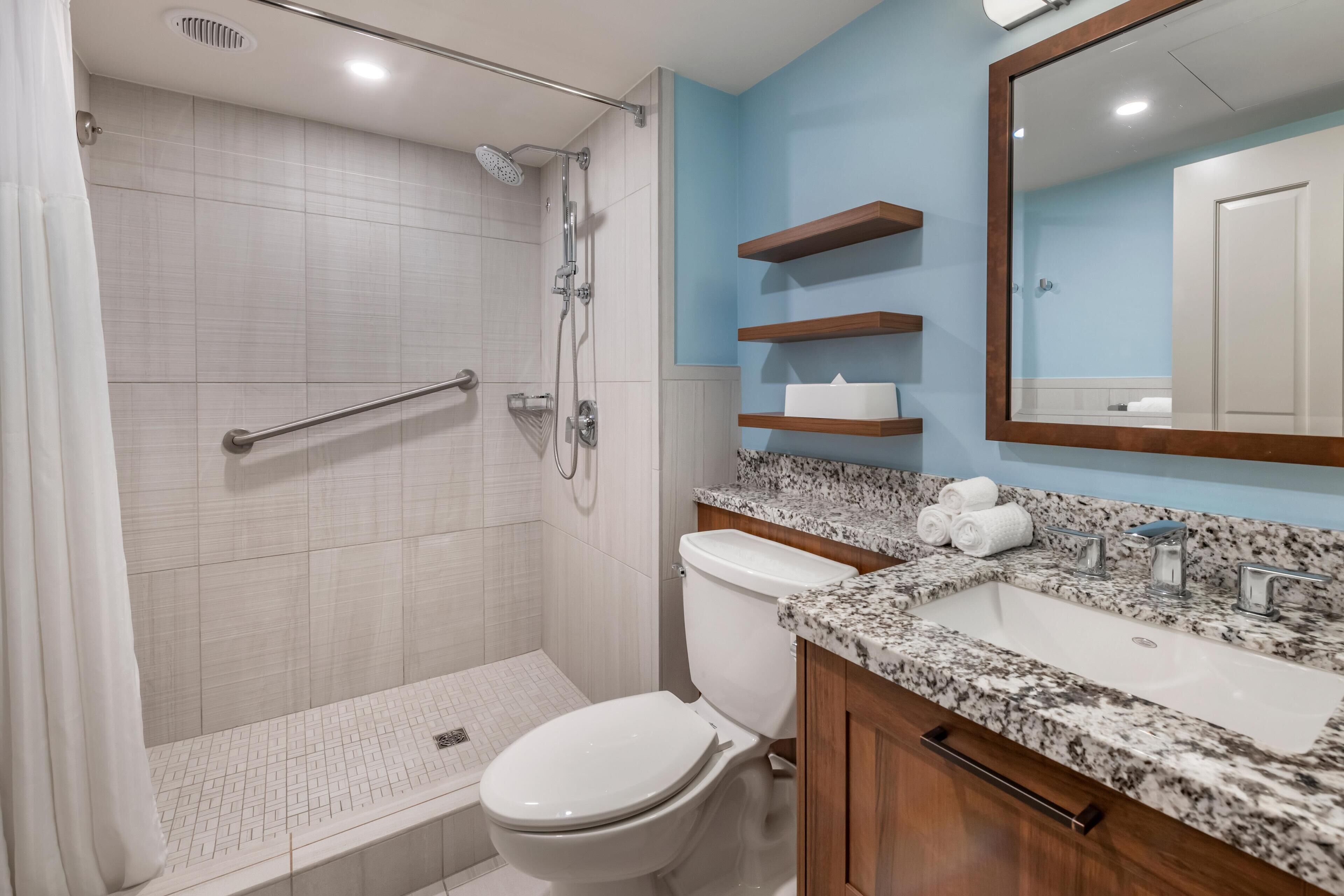 Une salle de bain équipée d’une douche, de toilettes, d’un lavabo et d’un comptoir en marbre.