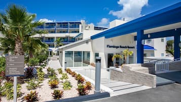 A modern hotel entrance with a sign indicating amenities like a pool, spa, bar, beach, and fitness center.