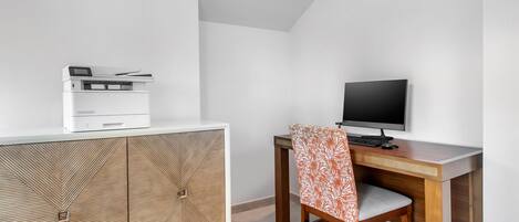 A modern office space with a white cabinet, a wooden desk, a computer monitor, and a printer.