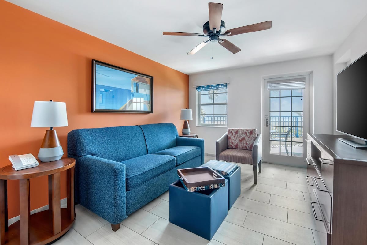 A modern living room with a blue sofa, a coffee table, a TV, and a ceiling fan.