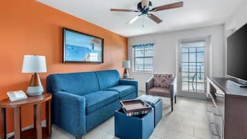 A modern living room with a blue sofa, a coffee table, a TV, and a ceiling fan.