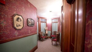 A hallway with patterned wallpaper, a small table with chairs, and a door leading to another room. - Hotel Ruby Marie (Madison)