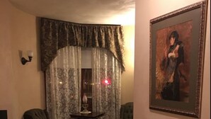 A living room with a fireplace, two armchairs, a small table, and a painting on the wall. - Hotel Ruby Marie (Madison)