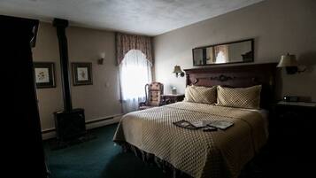 Une chambre d’hôtel avec un grand lit, une tête de lit en bois, une table de chevet, une lampe, un miroir et une fenêtre avec des rideaux.
