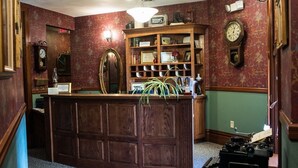 A room with a wooden desk, a bookshelf, a mirror, and a clock on the wall. - Hotel Ruby Marie (Madison)