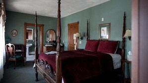 A traditional bedroom with a four-poster bed, a wooden chair, a bedside table, and a mirror. - Hotel Ruby Marie (Madison)