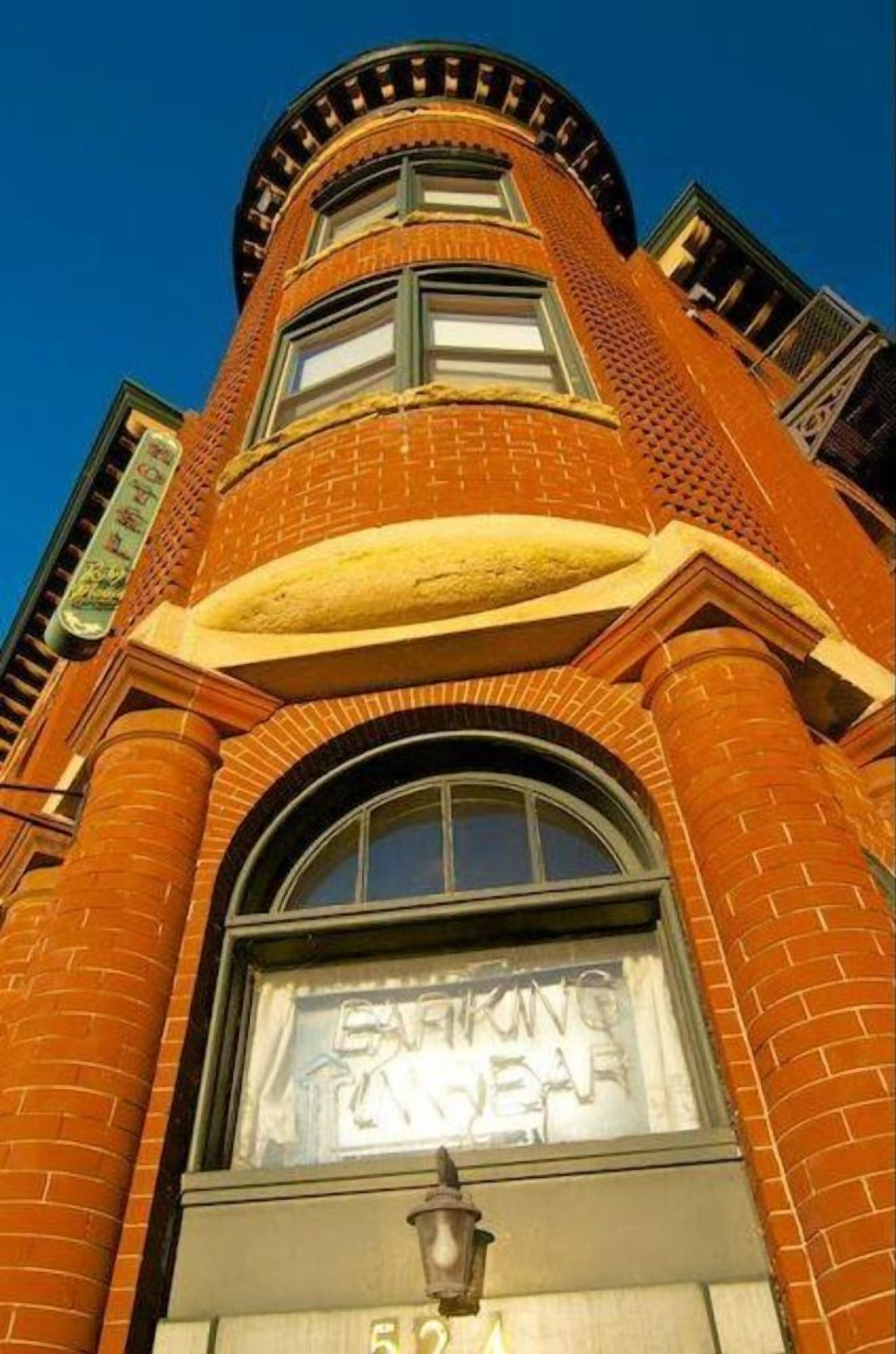 Un edificio de ladrillo con un gran ventanal arqueado y un cartel que dice 