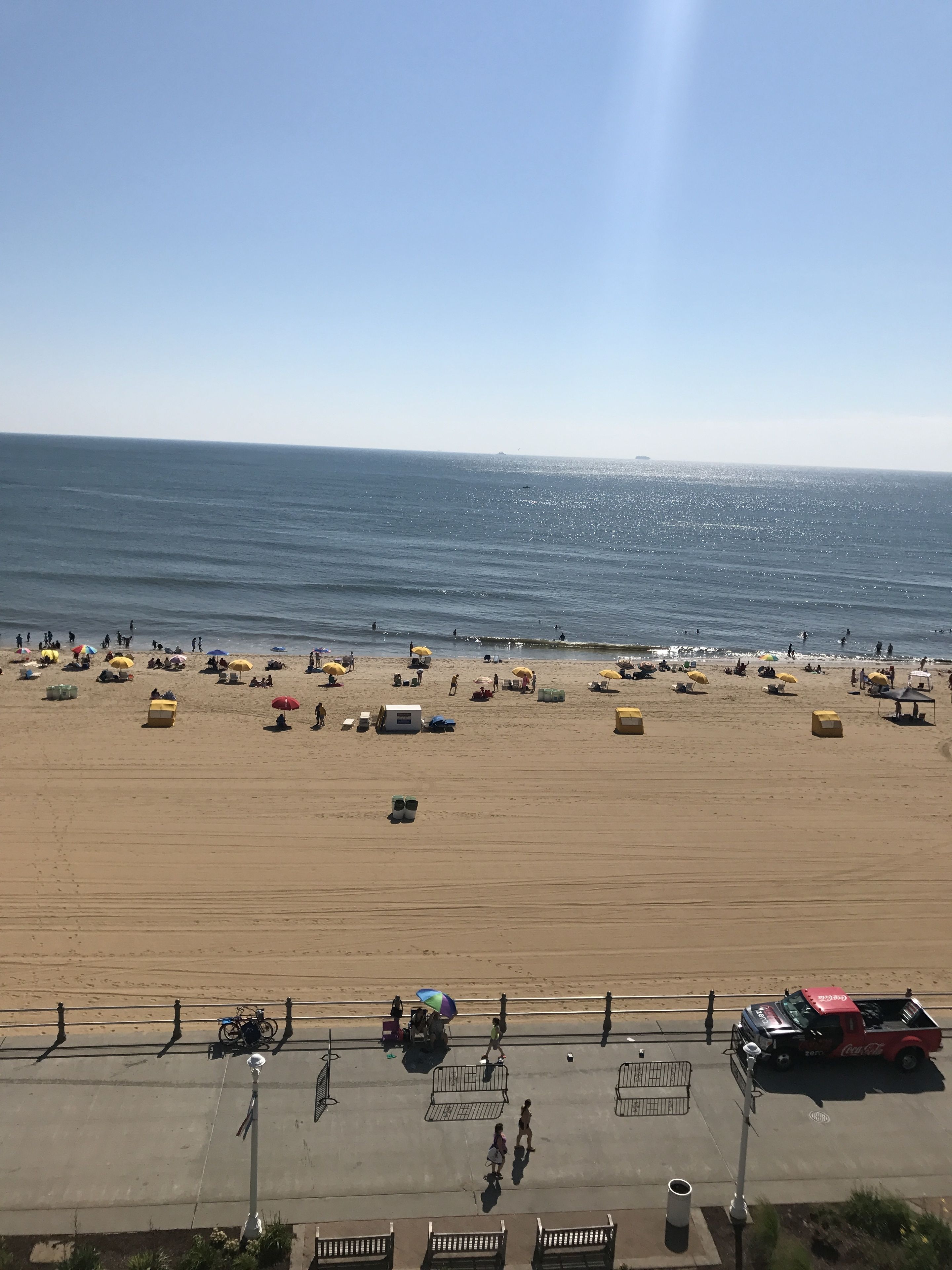 A beach with umbrellas, people, and a Coca-Cola truck.
