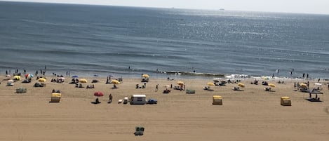 A beach with umbrellas, people, and a Coca-Cola truck.