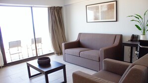 A modern living room with a sofa, a coffee table, and a potted plant. - Sun and Sand Resort Oceanfront Suites  (Virginia Beach)