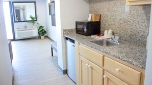 A modern kitchen with granite countertops, a built-in microwave, and a sink. - Sun and Sand Resort Oceanfront Suites  (Virginia Beach)