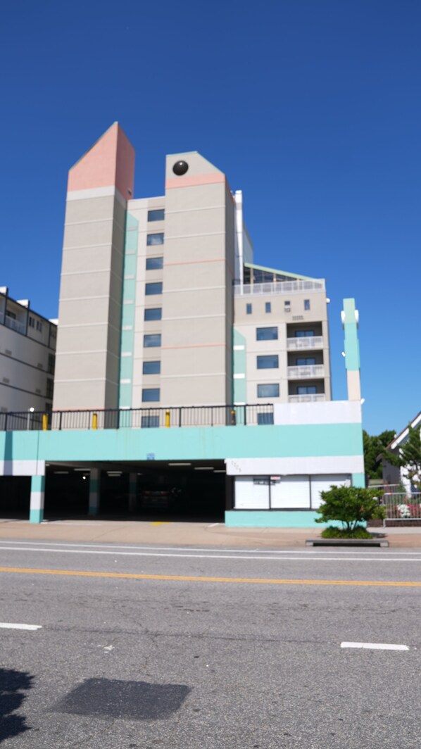 A multi-story building with a flat roof, a large garage entrance, and a small tree in front.