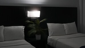 A hotel room with two beds, a nightstand with a lamp, and a potted plant. - Sun and Sand Resort Oceanfront Suites  (Virginia Beach)