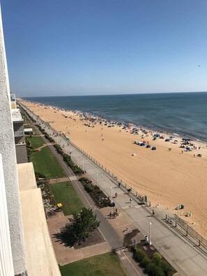 A beach with a paved walkway and a view of the ocean. - Sun and Sand Resort Oceanfront Suites  (Virginia Beach)