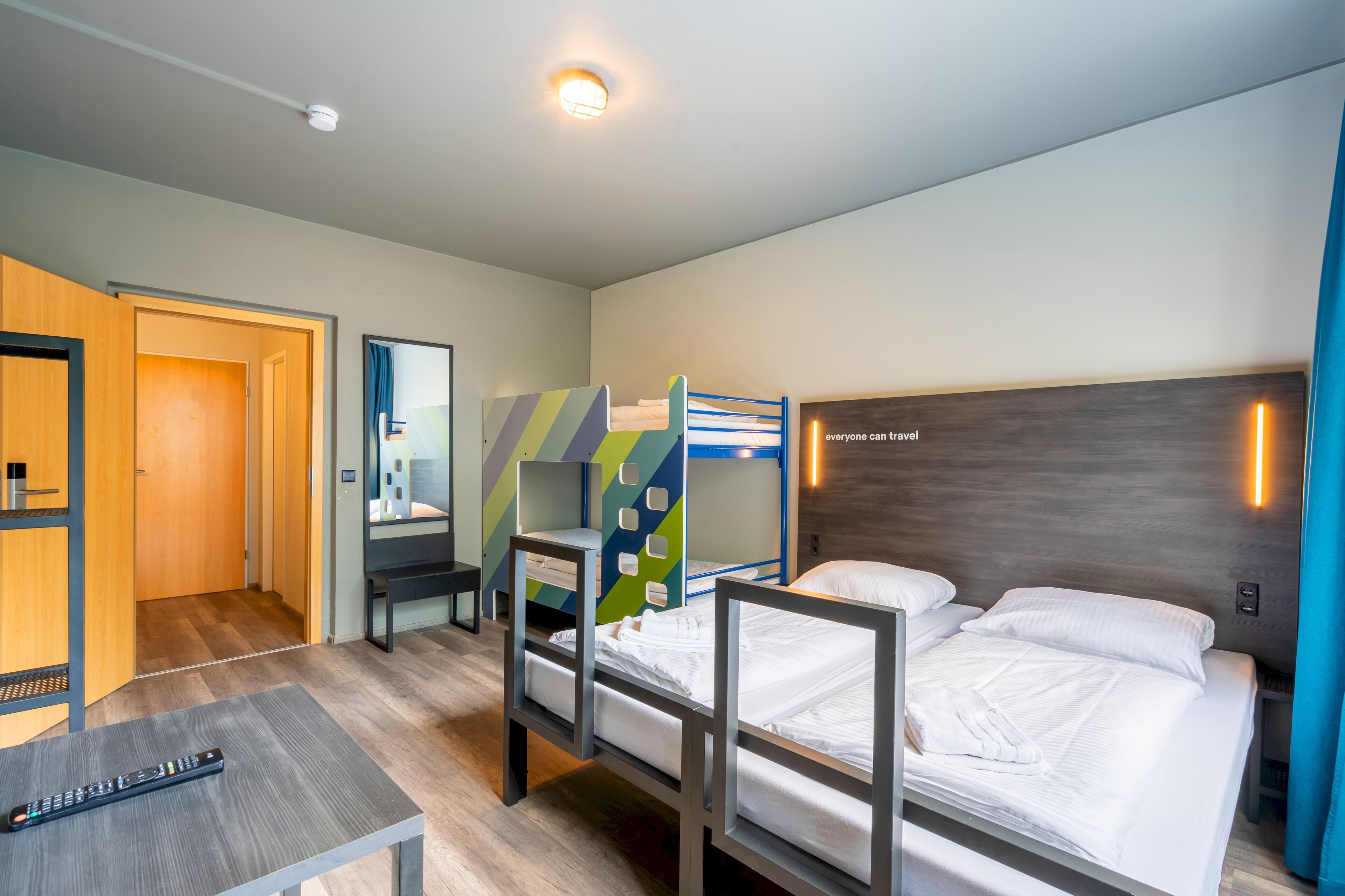 Een moderne hotelkamer met stapelbedden, een bureau en een spiegel.