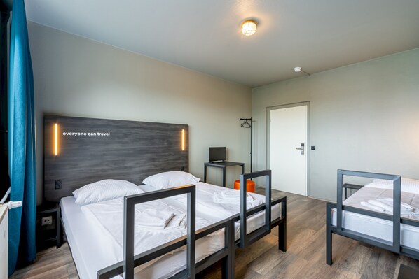 A hotel room with two beds, a desk, a chair, a wardrobe, and a mirror. - a&o Berlin Kolumbus (Berlin)