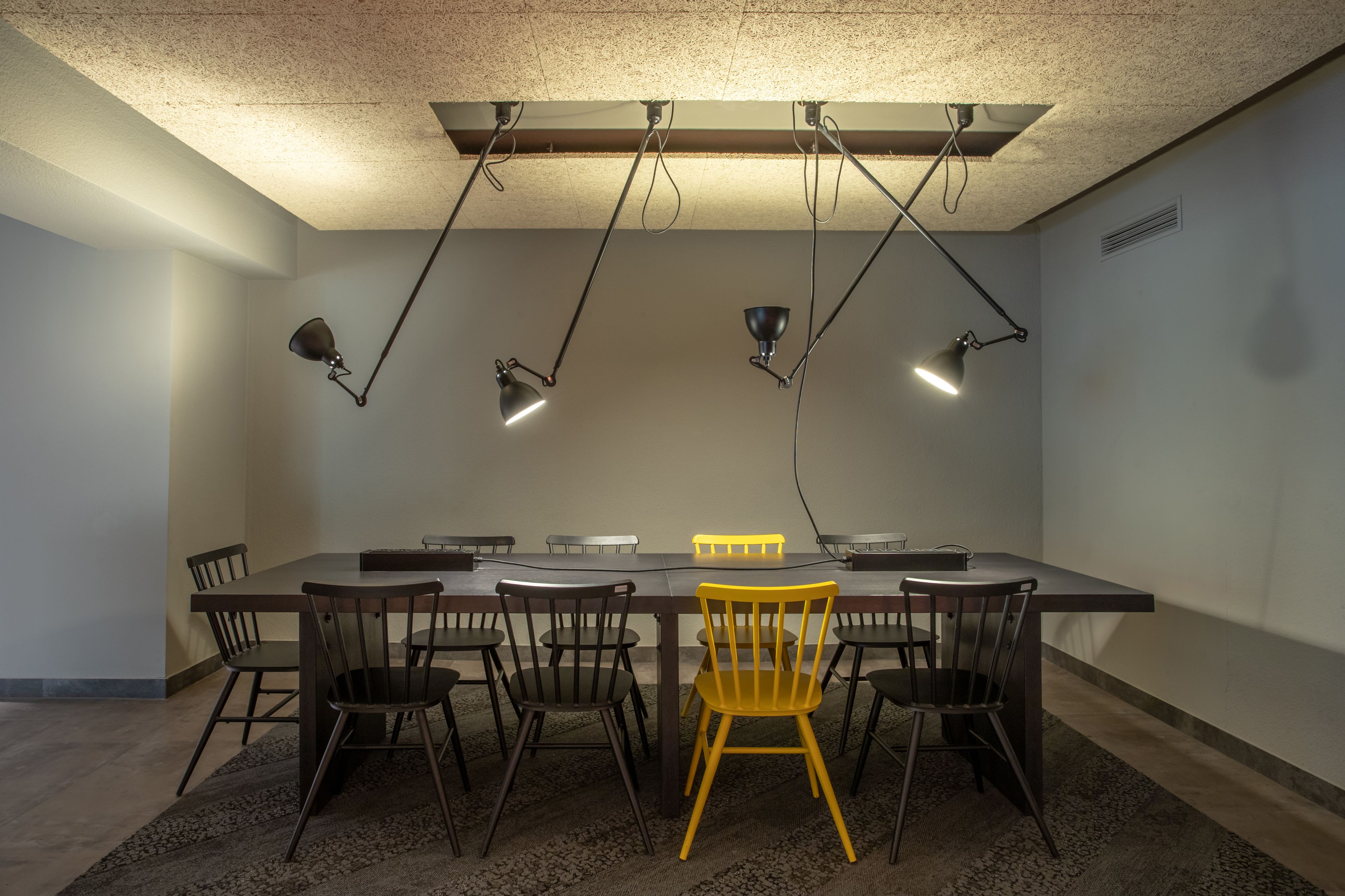 Una sala conferenze con un lungo tavolo, diverse sedie e illuminazione a soffitto.