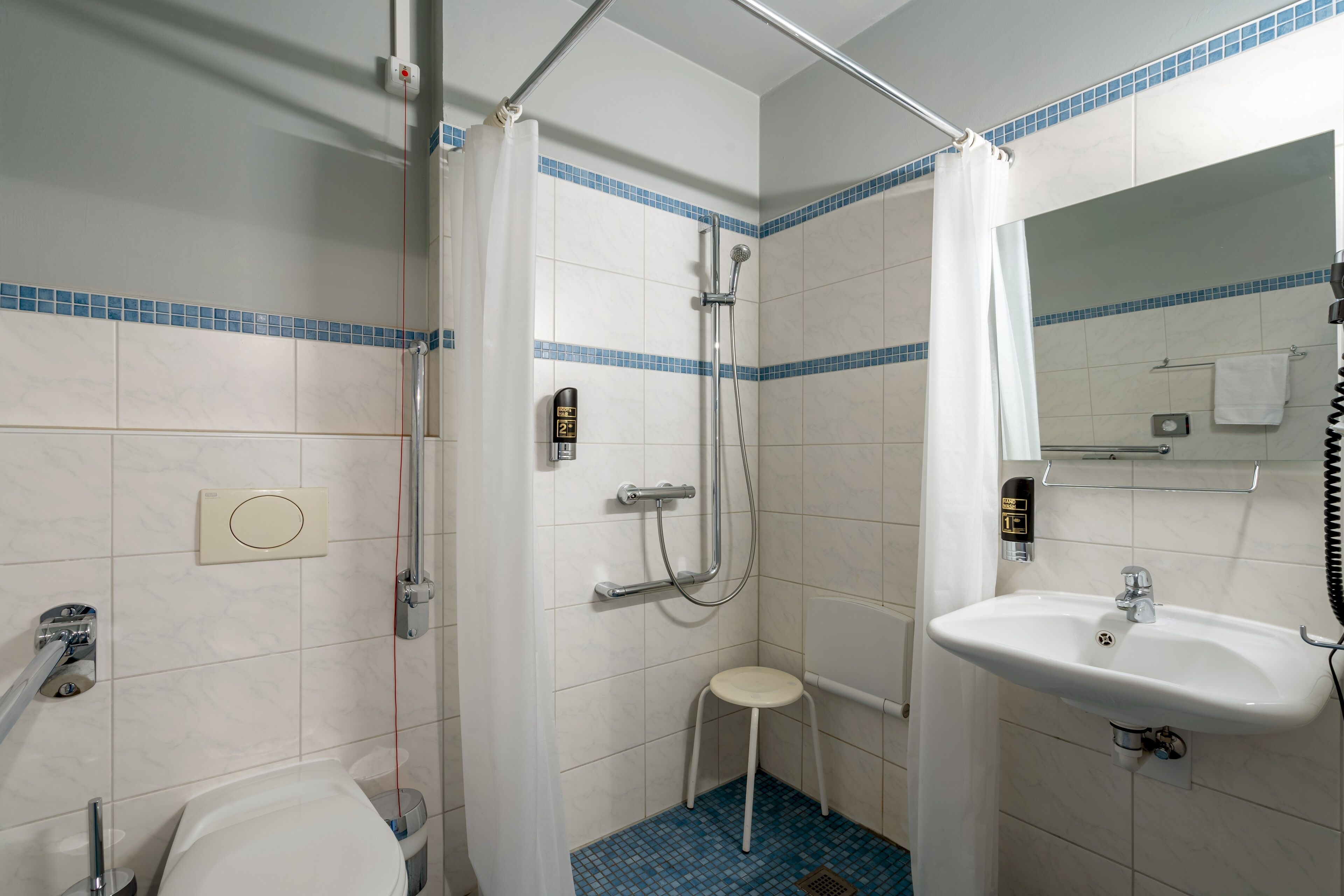 Et badeværelse med brusebad, toilet og håndvask.
