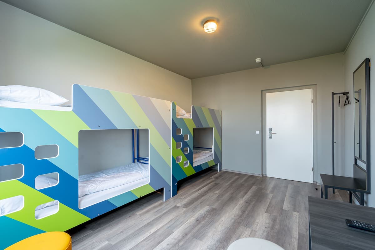 A room with bunk beds, a desk, and a door.