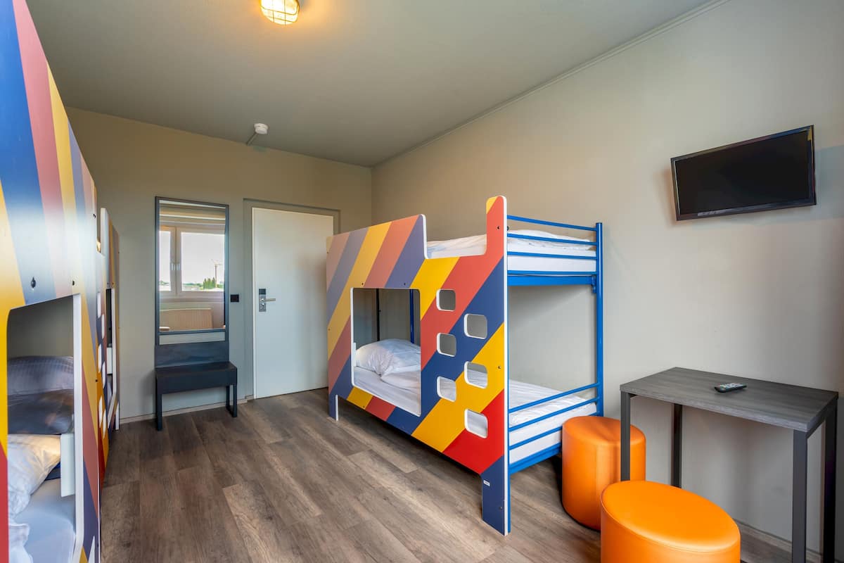 A room with bunk beds, a desk, and a TV.