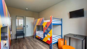 Quarto com beliches, uma mesa e uma televisão.