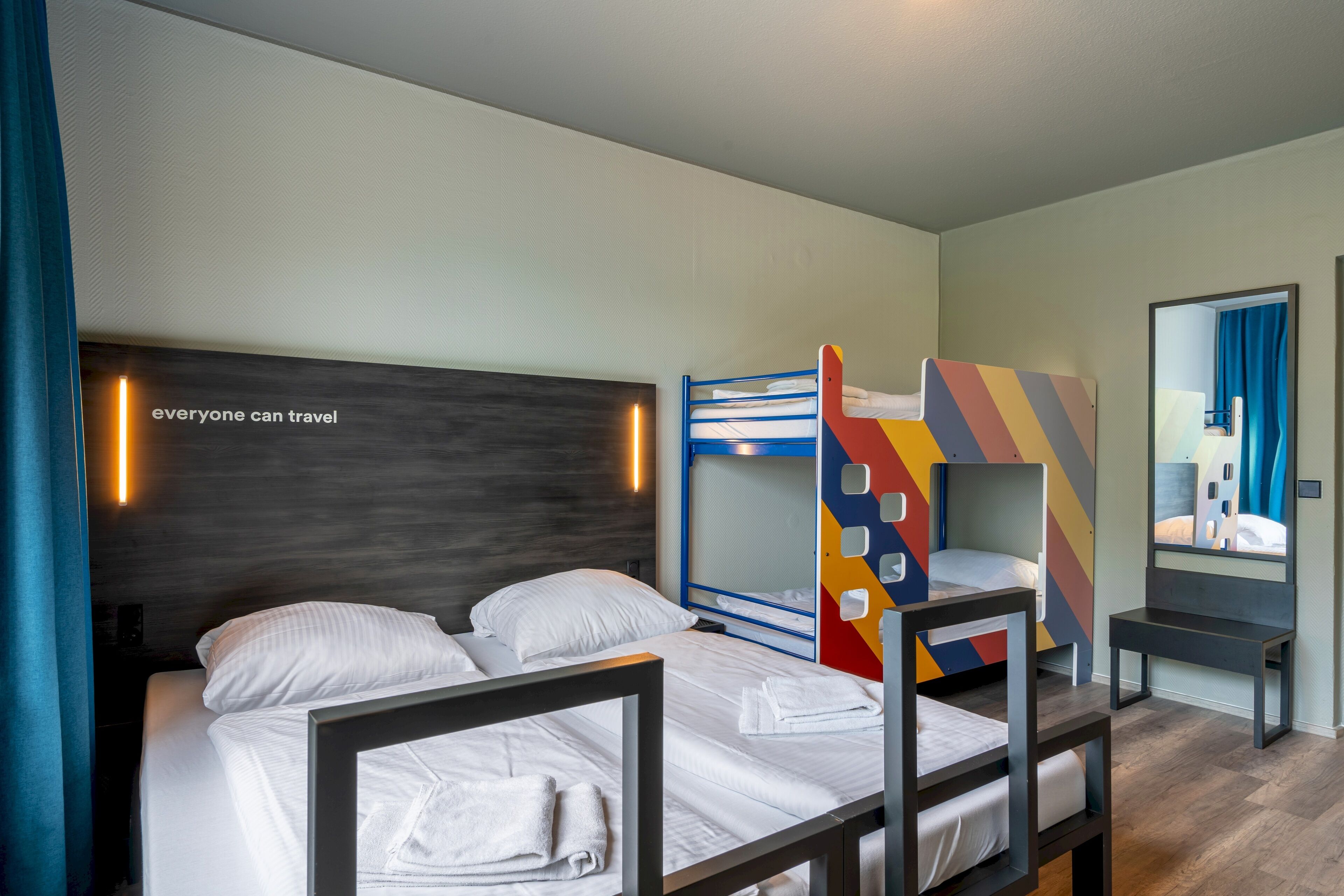 Habitación de hotel con literas, un escritorio y un espejo.