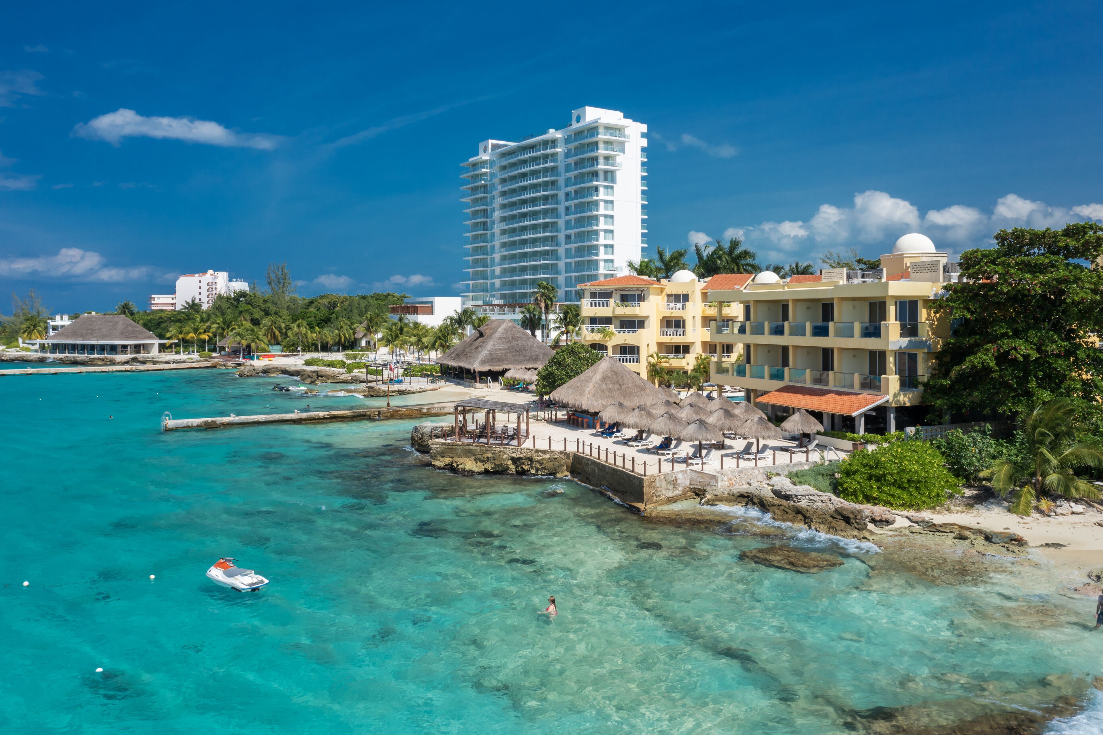 A coastal hotel with a beach view, a pier, and a large hotel building in the background.