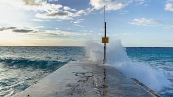 A pier extending into the ocean with waves crashing against it.