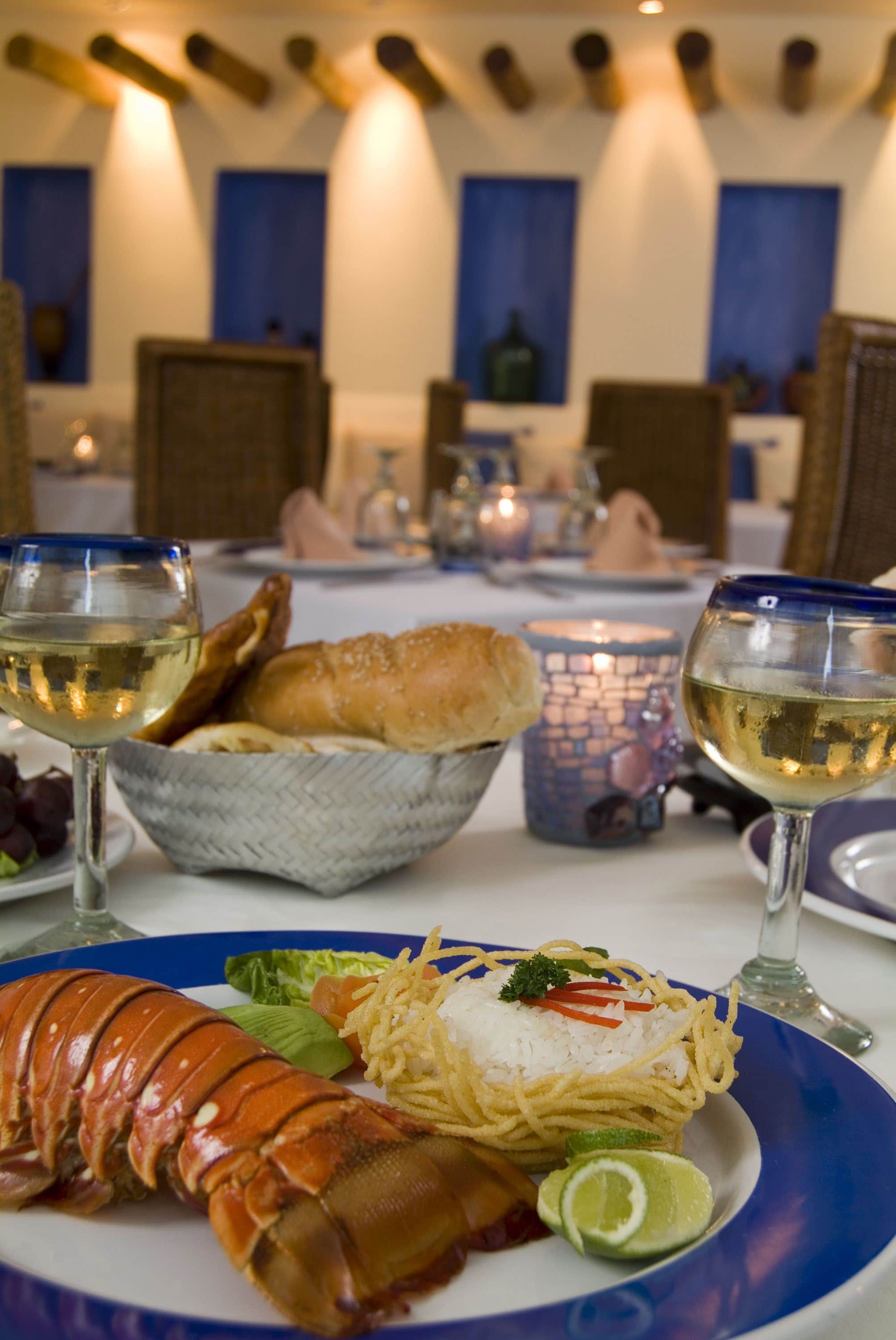 Une table à manger avec un homard, du pain et des verres à vin.