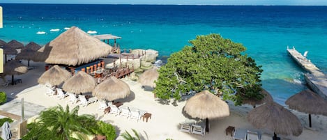 Een privéstrand, wit zand, ligstoelen aan het strand, parasols