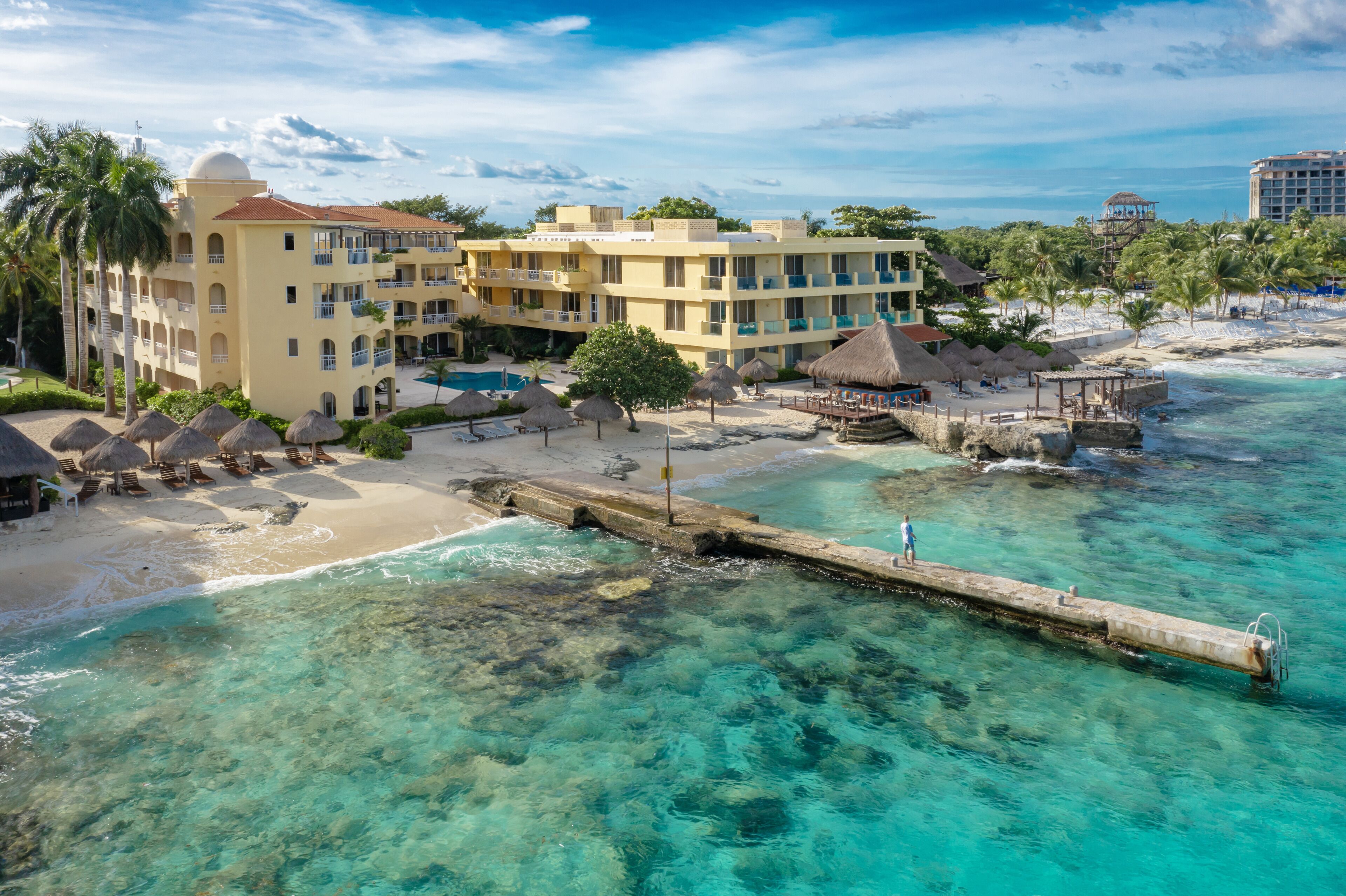 A resort with multiple buildings, a beach, and a pier.