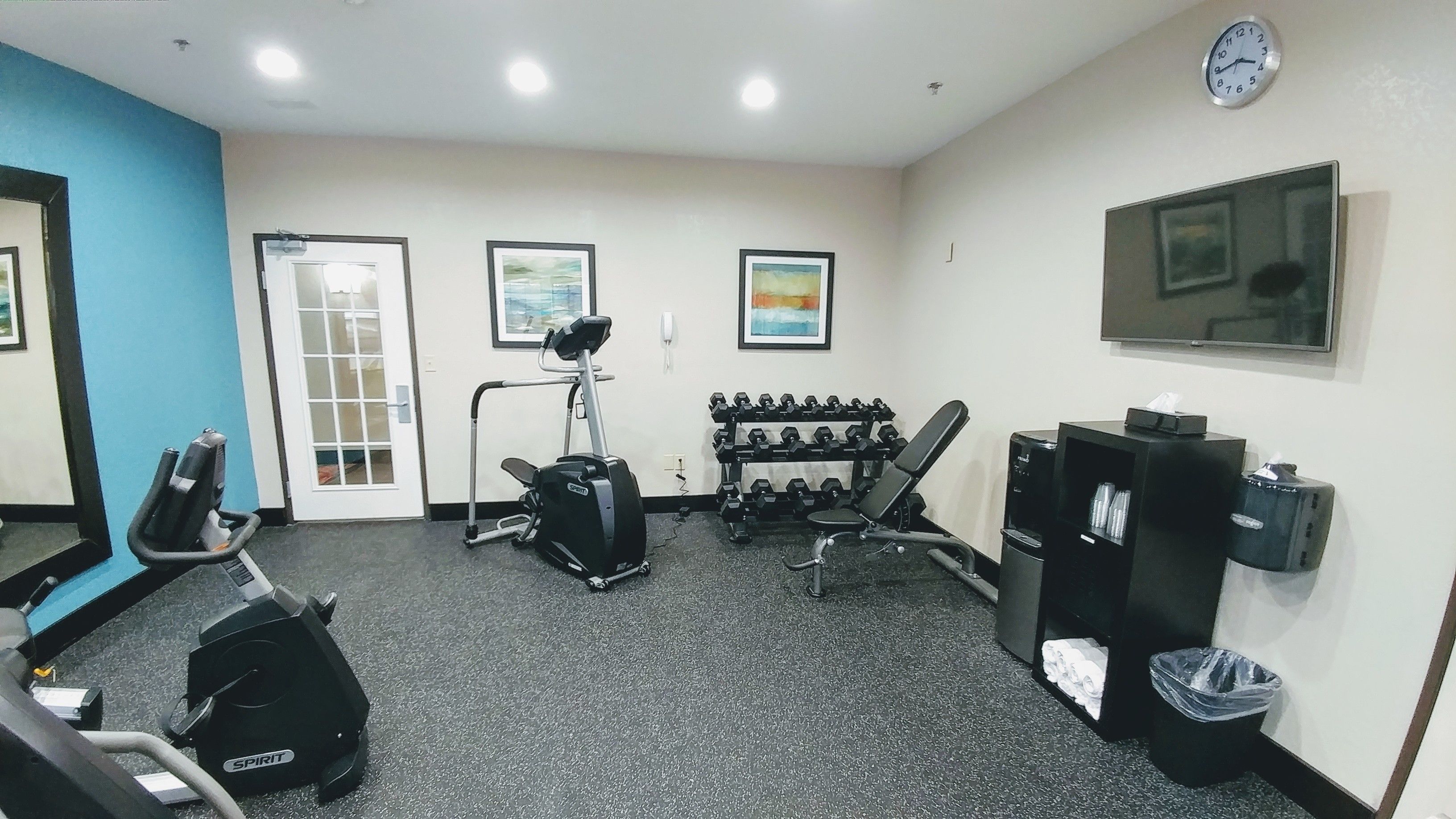 A gym with cardio equipment, dumbbells, and a treadmill.