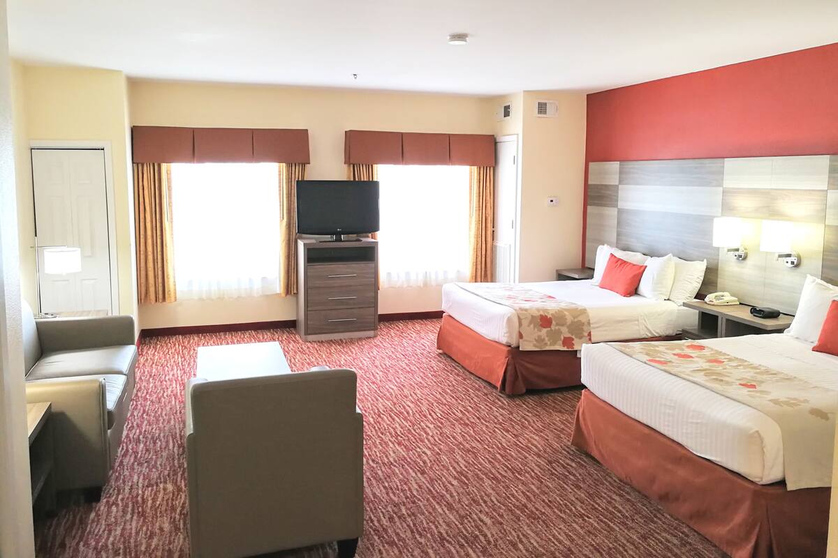 A hotel room with two beds, a TV, a desk, and a chair.