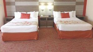 A hotel room with two beds, a red carpet, and a modern headboard with a light fixture.