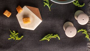 A bowl of soup with croutons and a swirl of cream on a dark cloth.